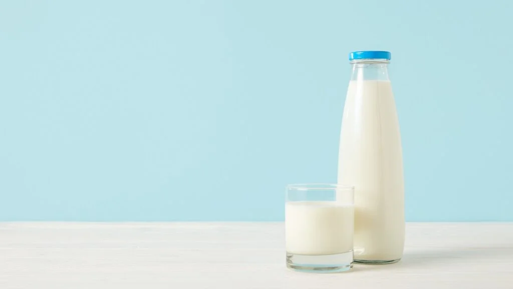 garrafa e copo de leite sobre a mesa. a alergia ao leite ou APLV exige cuidados